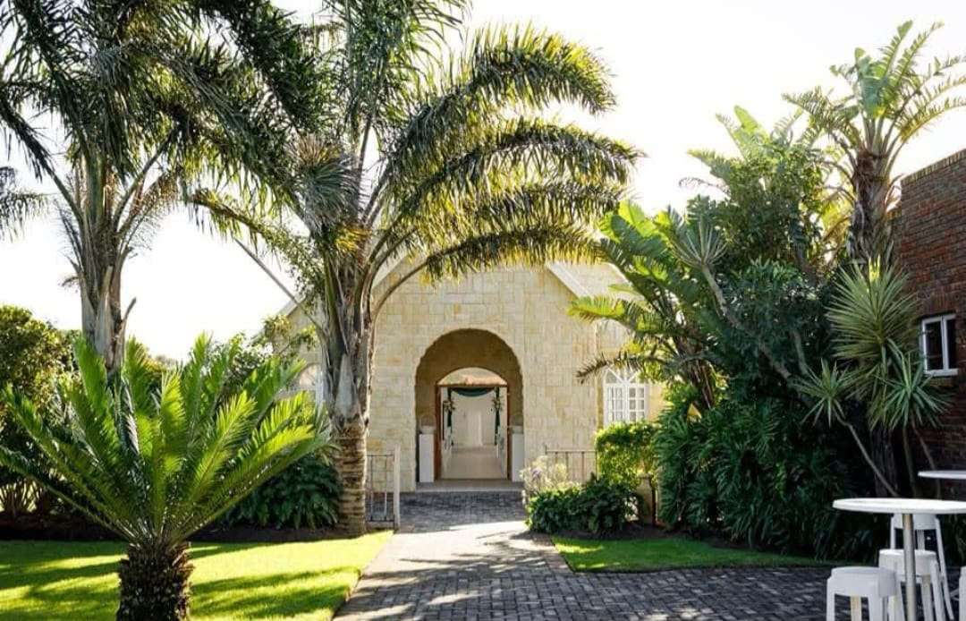 The stone Indoor Chapel framed by palms on a sunny day