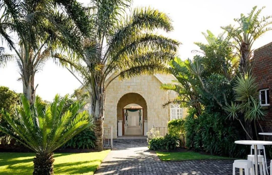 The stone Indoor Chapel framed by palms and cycads in the Ukuphupha garden