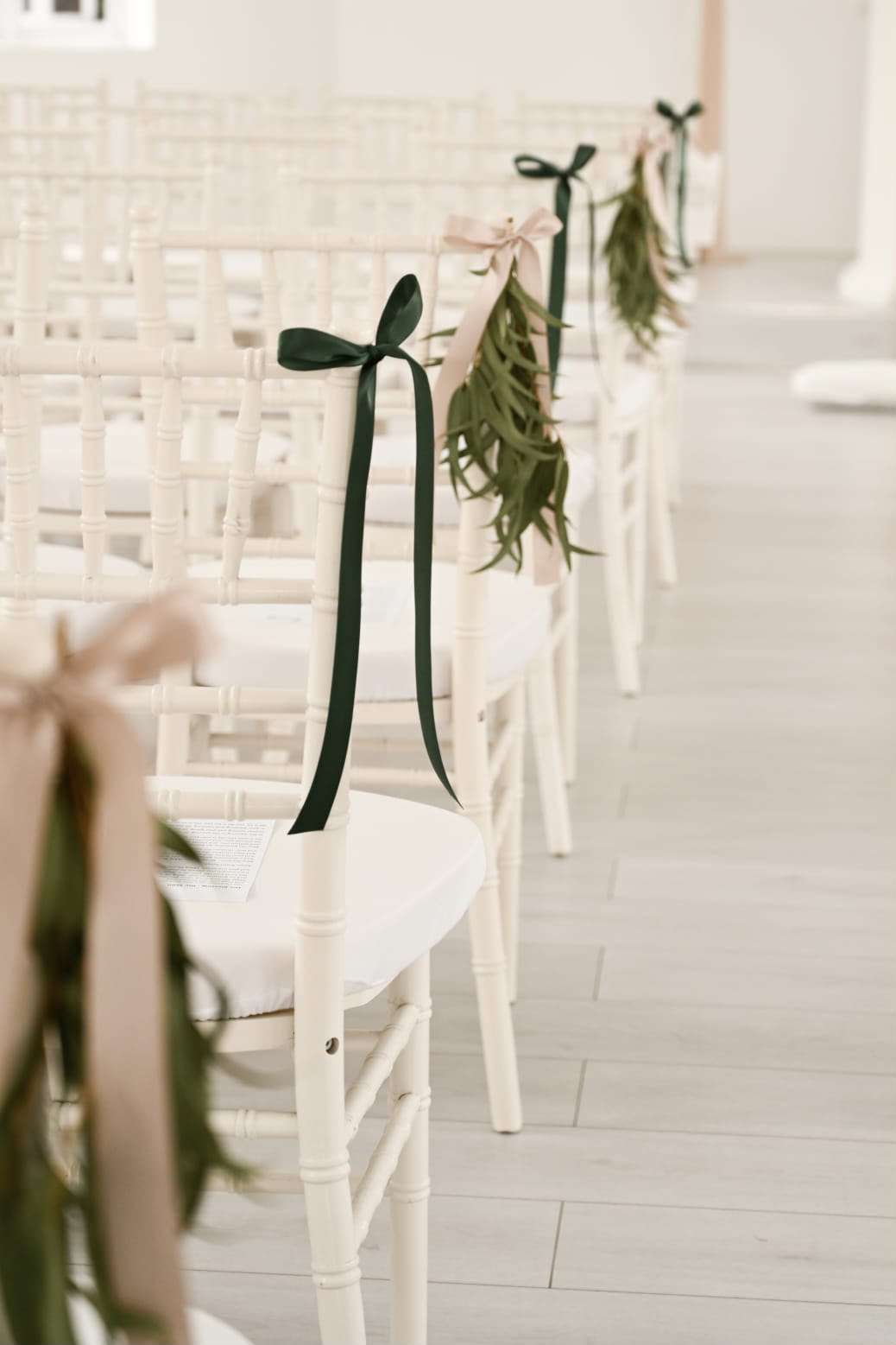 Indoor Chapel chairs tied with dark green ribbon and trailing foliage