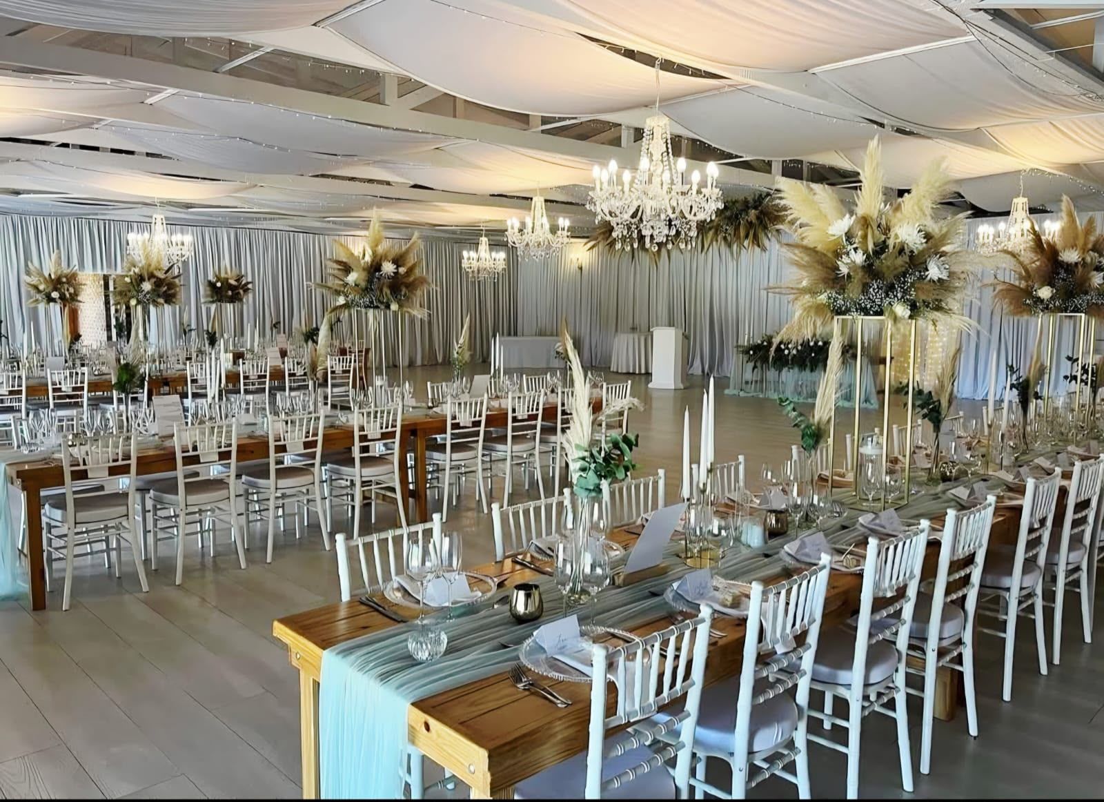The Main Hall dressed for a reception with long tables, chandeliers and pampas centrepieces